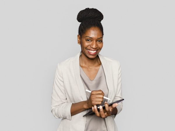 Smiling woman writing notes on tablet digital device