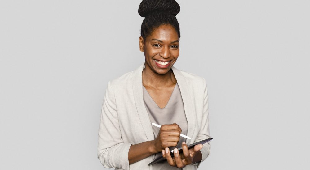 Smiling woman writing notes on tablet digital device